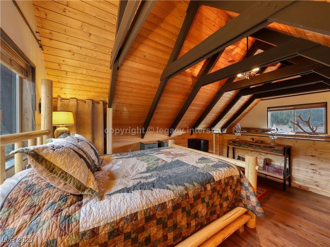 Bedroom with vaulted ceiling with beams, wood finished floors, wooden walls, and wooden ceiling | Image 27