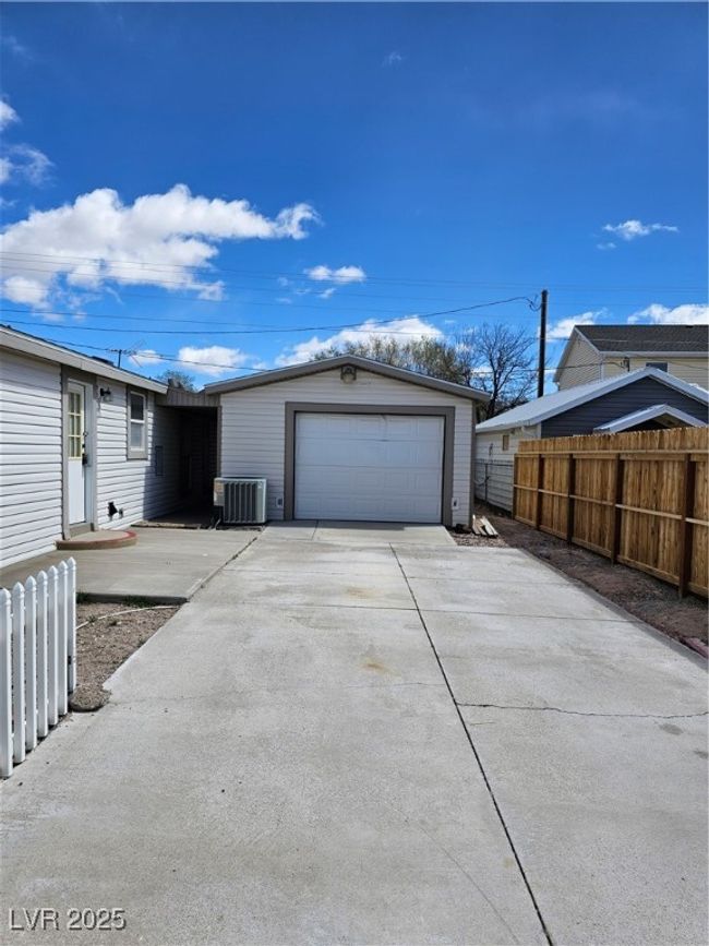 Garage with concrete driveway, central AC unit, and fence | Image 5