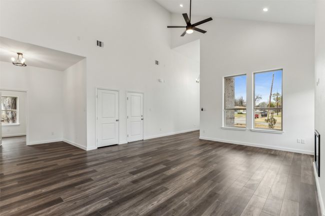 Unfurnished living room featuring a high ceiling, plenty of natural light, a ceiling fan, dark wood-type flooring, and recessed lighting | Image 14