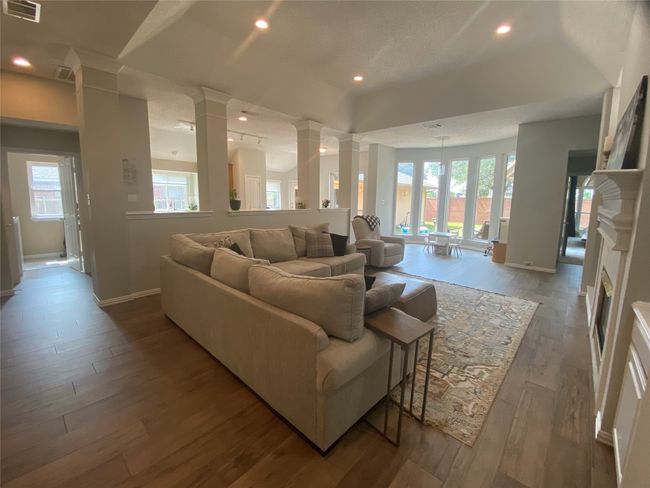 Living room featuring ornate columns, plenty of natural light, wood finished floors, baseboards, and recessed lighting | Image 9