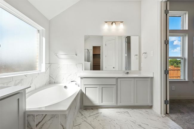 Bathroom featuring vanity, a garden tub, healthy amount of natural light, lofted ceiling, and marble finish floors | Image 25