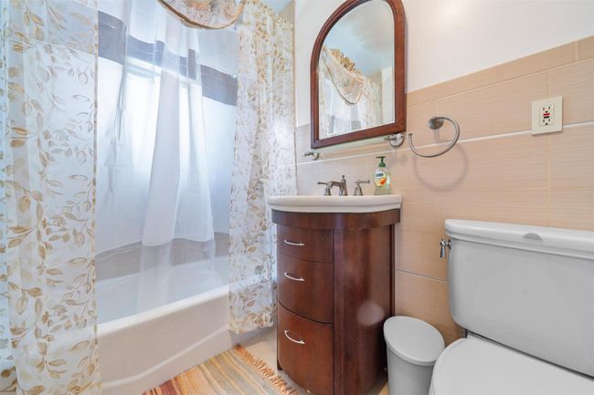 Bathroom featuring tile walls, toilet, shower / bath combo, and vanity | Image 16
