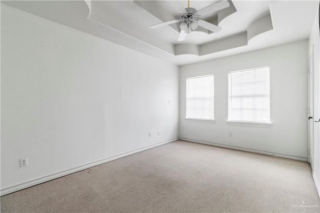 Unfurnished room with a tray ceiling, a ceiling fan, and carpet | Image 11