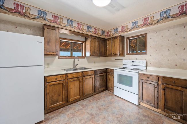 Kitchen with white appliances, light countertops, brown cabinets, and light floors | Image 13