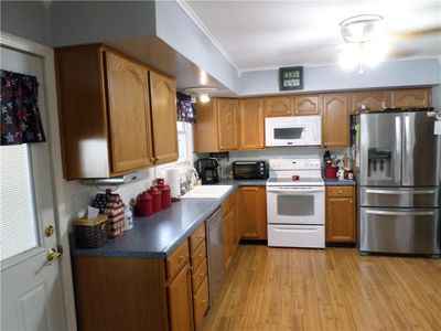 Kitchen featuring light hardwood / wood-style floors, crown molding, appliances with stainless steel finishes, and sink | Image 3