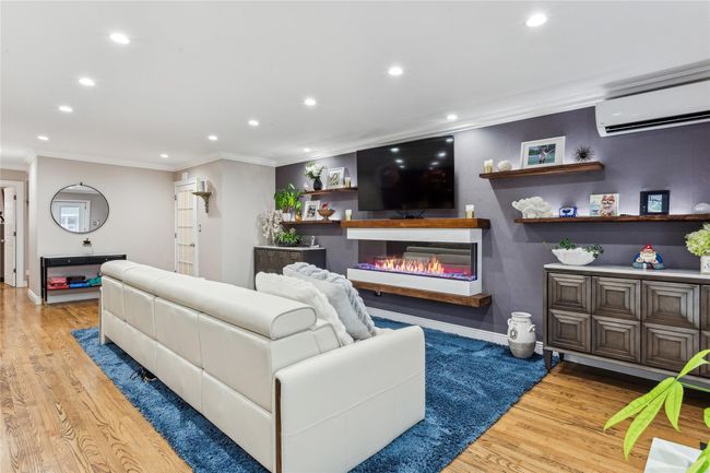 Living room with crown molding, light hardwood / wood-style floors, and an AC wall unit | Image 9