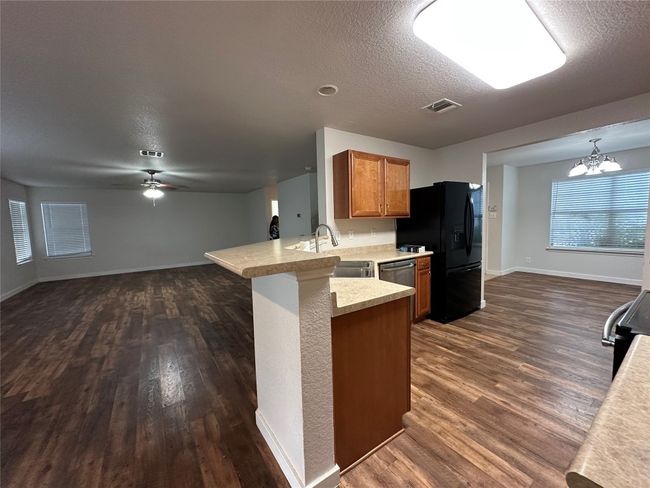 Kitchen with a peninsula, dark wood-type flooring, light countertops, ceiling fan, and open floor plan | Image 8
