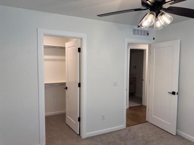 Unfurnished bedroom with carpet floors, ceiling fan, a walk in closet, baseboards, and visible vents | Image 35