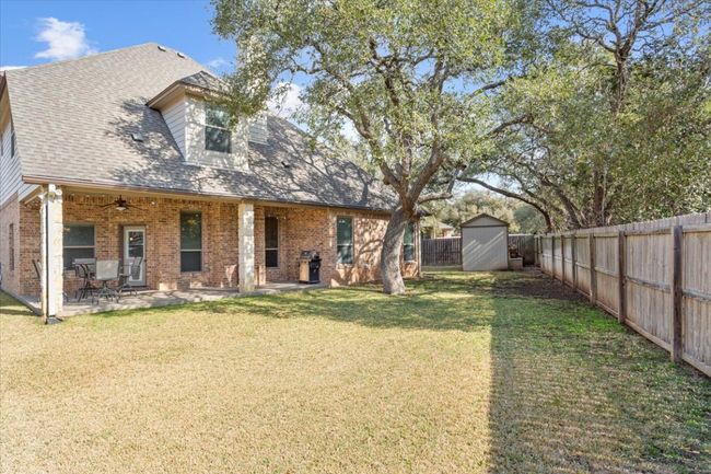 Back of property featuring brick siding, a storage shed, a yard, an outdoor structure, and a fenced backyard | Image 36