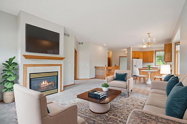Spacious open concept living room with natural gas burning fireplace, neighboring informal dining area & kitchen. Door leading out to large back deck (28x10). (virtually staged) | Image 6