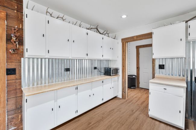 Kitchen with white cabinets, light wood-style floors, light countertops, stainless steel microwave, and recessed lighting | Image 9