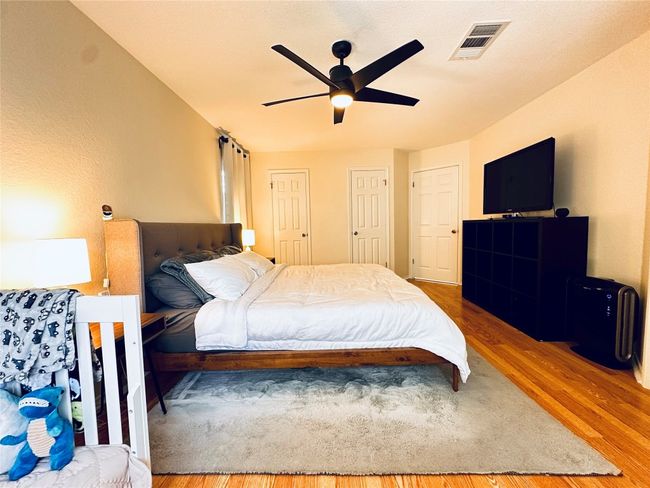 Bedroom with visible vents, a ceiling fan, two closets, and wood finished floors | Image 14