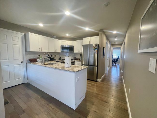 Kitchen featuring stainless steel appliances, a peninsula, a sink, and light stone countertops | Image 13