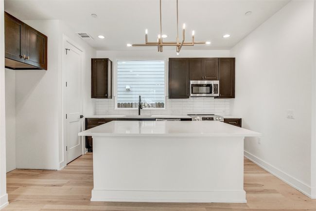 Kitchen with appliances with stainless steel finishes, a sink, backsplash, dark brown cabinets, and recessed lighting | Image 15