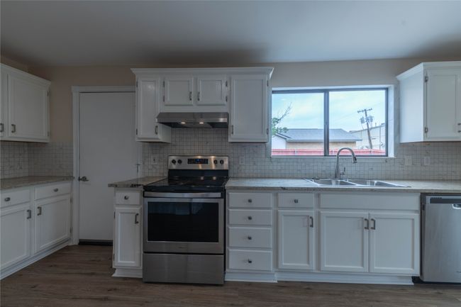 Kitchen featuring stainless steel appliances, a sink, extractor fan, white cabinets, and backsplash | Image 8