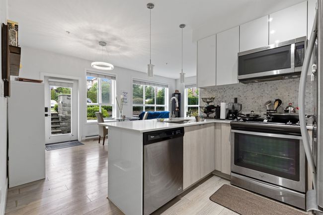 Kitchen featuring stainless steel appliances, modern cabinets, a peninsula, tasteful backsplash, and light countertops | Image 38