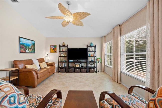 Living room with lofted ceiling, light tile patterned flooring, ceiling fan, and visible vents | Image 19