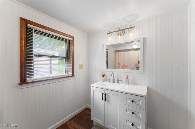 Full bath with crown molding, vanity, wood finished floors, and wooden walls | Image 13
