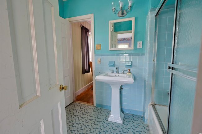 Bathroom with tile patterned floors, tile walls, bathtub / shower combination, and wainscoting | Image 12