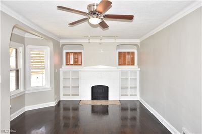 Unfurnished living room featuring dark wood-type flooring, a wealth of natural light, ornamental molding, and rail lighting | Image 3