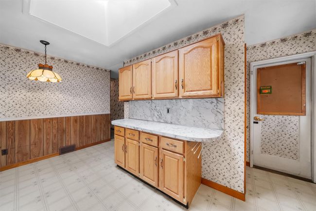 Kitchen with light countertops, hanging light fixtures, light floors, and wallpapered walls | Image 15