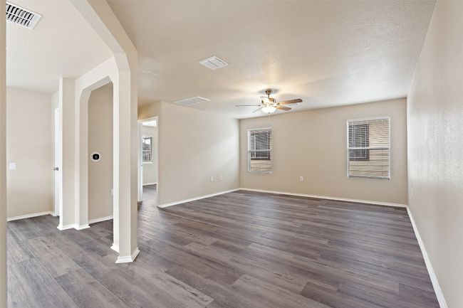 Empty room with ceiling fan, dark wood-style floors, and arched walkways | Image 6