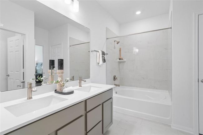 This primary bathroom is definitely move-in ready! Featuring dual vanities, stained cabinets with light countertops, spacious walk-in closet with shelving, high ceilings, neutral paint, sleek and modern finishes. | Image 18