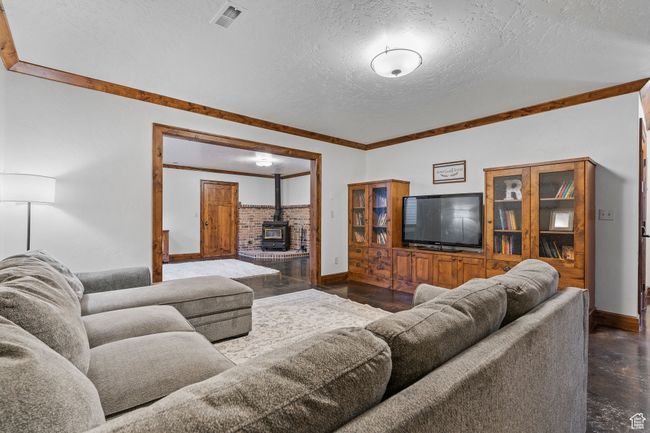 Living room with crown molding, a wood stove, and a textured ceiling | Image 38