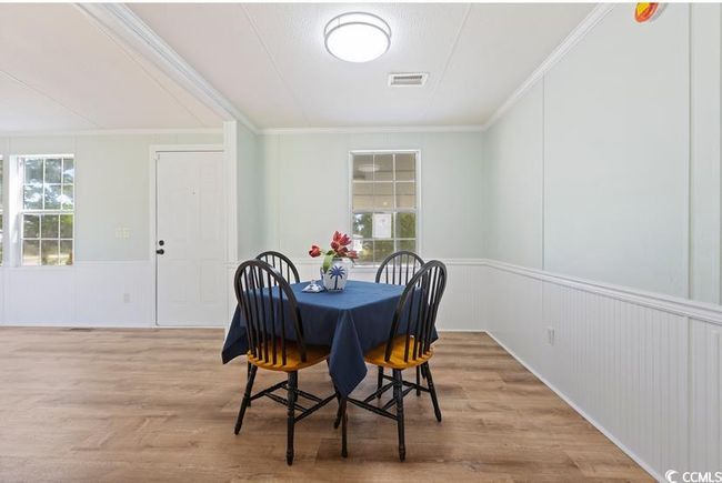 Dining room featuring crown molding, wood finished floors, a wainscoted wall, and a decorative wall | Image 13