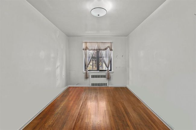 Unfurnished room featuring hardwood / wood-style flooring and radiator | Image 6