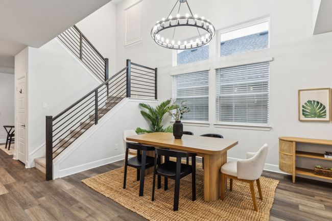 Dining area with wood finished floors, stairs, a chandelier, baseboards, and a high ceiling | Image 9