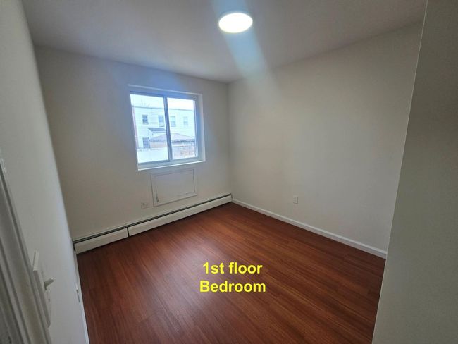 Empty room with a baseboard radiator, dark wood-style flooring, and baseboards | Image 6