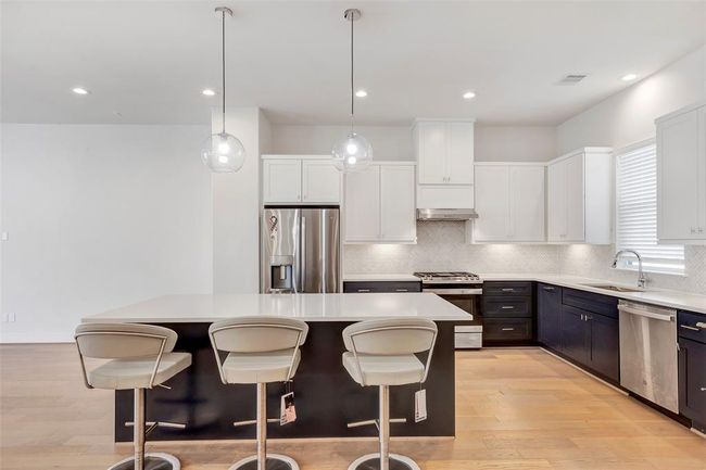 The beautiful kitchen features sleek quartz countertops and is equipped with modern stainless steel appliances and hanging cabinets. | Image 10
