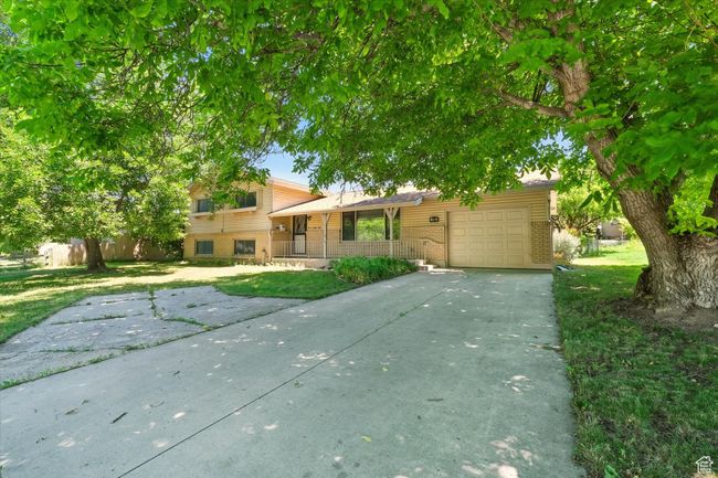 Tri-level home featuring brick siding, a garage, driveway, a porch, and a front lawn | Image 23