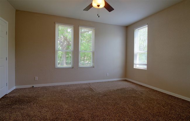 Carpeted empty room featuring a textured wall, baseboards, and ceiling fan | Image 11