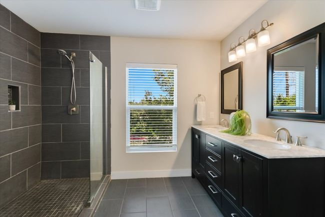 Primary bathroom with moody finish outs, a large walk in shower that features dual shower heads | Image 15