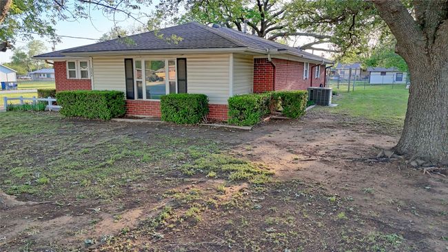 View of home's exterior with cooling unit, fence, brick siding, a shingled roof, and a yard | Image 13