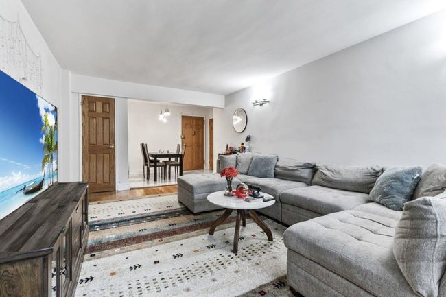 Living area with wood finished floors and a chandelier | Image 6