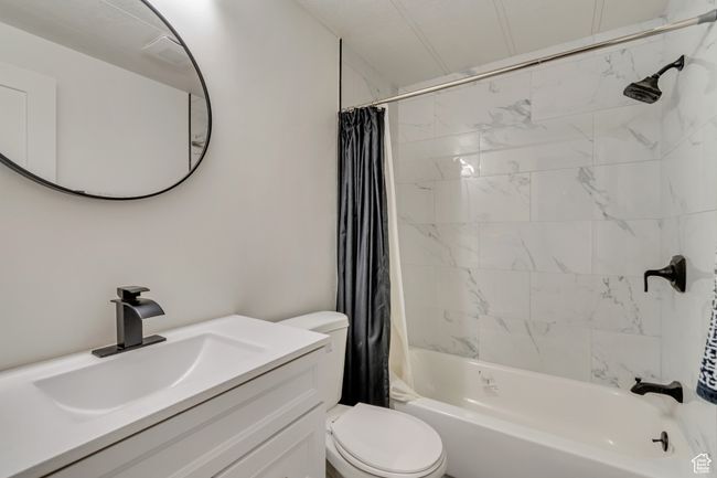Full bathroom featuring shower / tub combo with curtain, vanity, and toilet | Image 9
