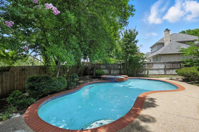 View of swimming pool featuring a fenced backyard and a pool with connected hot tub | Image 25