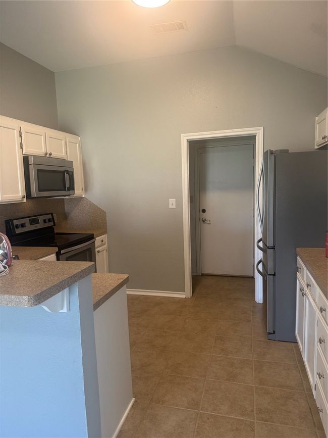 Kitchen with range, fridge, white cabinets, lofted ceiling, and light tile patterned flooring | Image 26