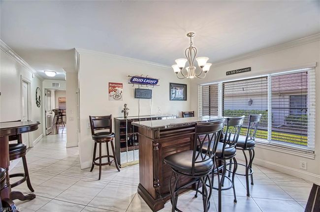 Dining room featuring a dry bar, light tile patterned flooring, an inviting chandelier, and crown molding | Image 17