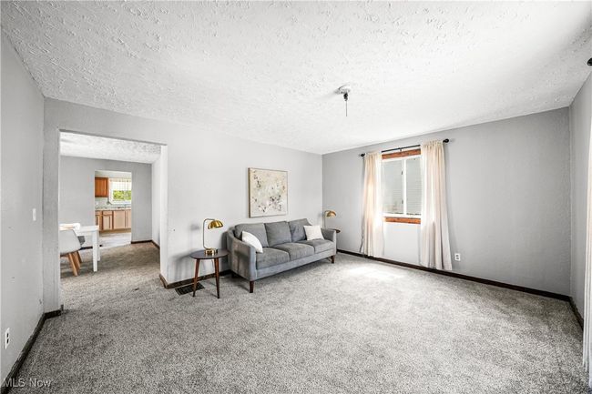 Carpeted living area with a textured ceiling and baseboards | Image 9
