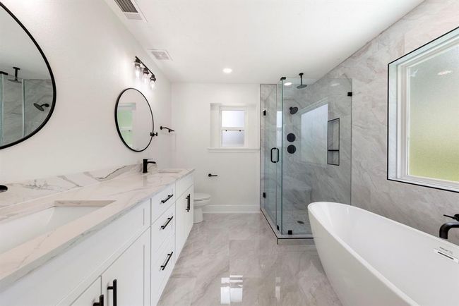 Stunning details in primary bath feature seamless glass shower and standalone soaking tub. | Image 17