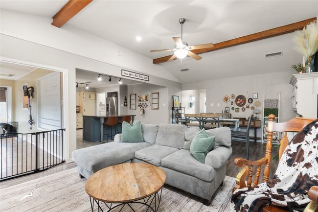 Living area featuring vaulted ceiling with beams, ceiling fan, visible vents, and light wood-style flooring | Image 7