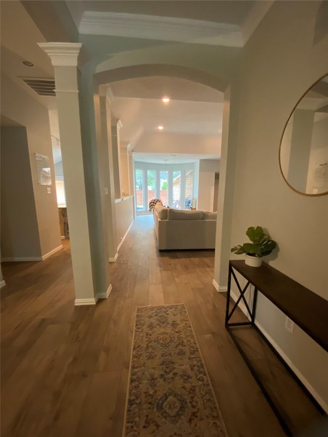 Hall with wood tiled floors, decorative columns, visible vents, baseboards, and arched walkways | Image 5