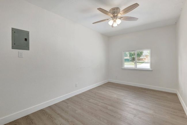Empty room with electric panel, light wood-type flooring, ceiling fan, and baseboards | Image 22