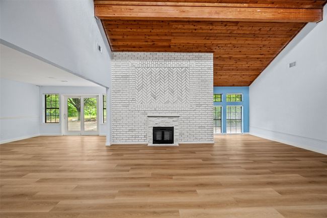 Unfurnished living room with high vaulted ceiling, a brick fireplace, healthy amount of natural light, and light wood-type flooring | Image 27