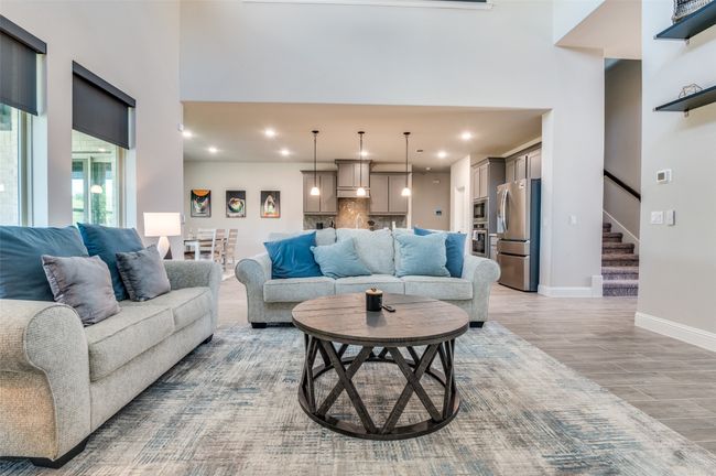 Living area featuring a high ceiling, light wood finished floors, stairs, and recessed lighting | Image 7