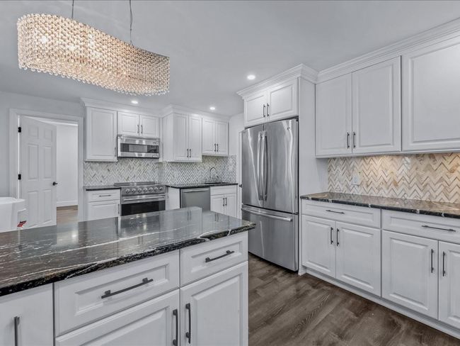 Kitchen with appliances with stainless steel finishes, white cabinets, a chandelier, recessed lighting, and dark wood-type flooring | Image 8
